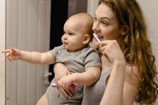 July 2023 Blog - A mom brushing her baby's teeth
